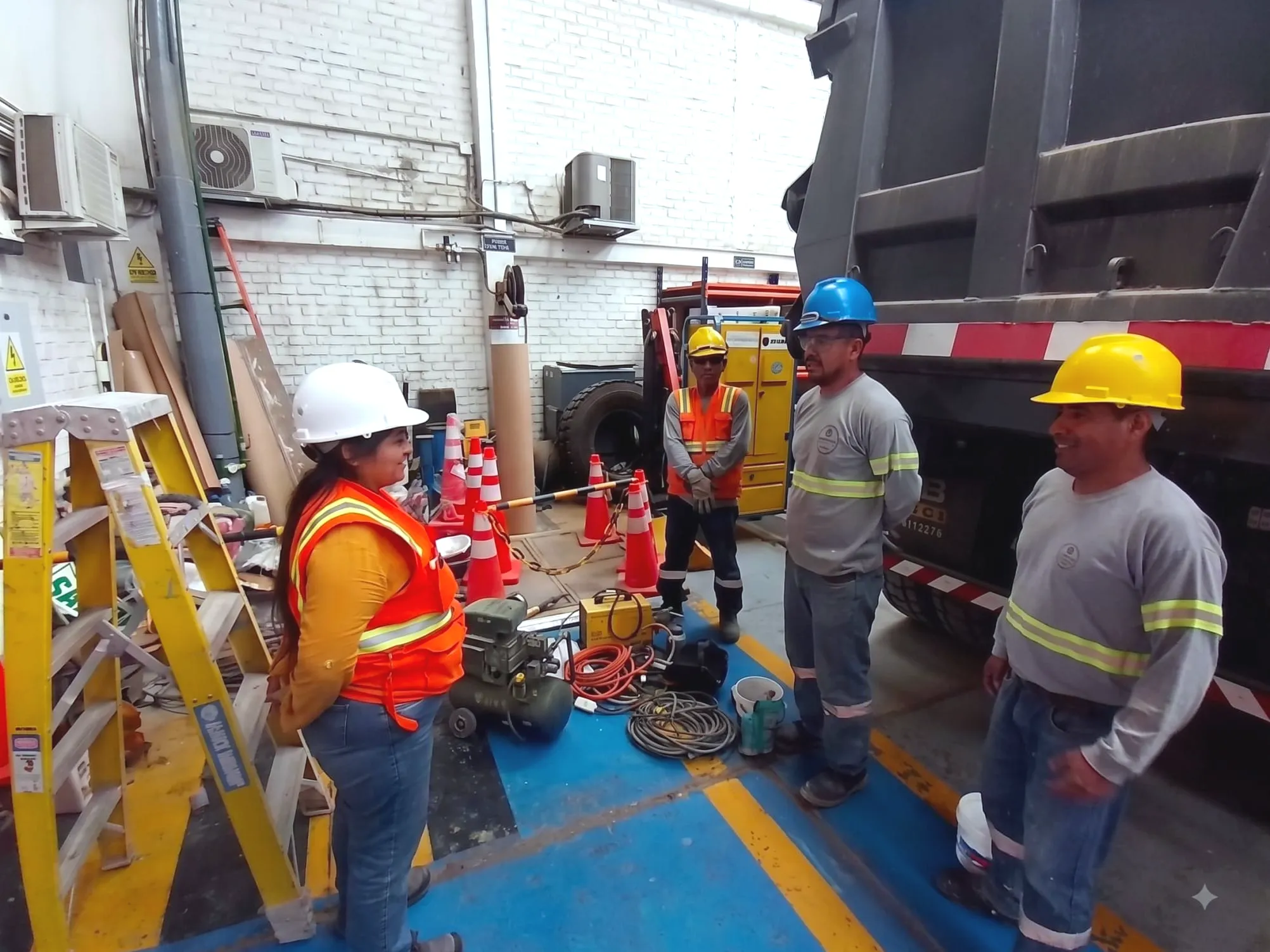 Cuadrilla de Arqdeco descargando equipos junto al camión, con escaleras, conos y la zona de trabajo ya delimitada