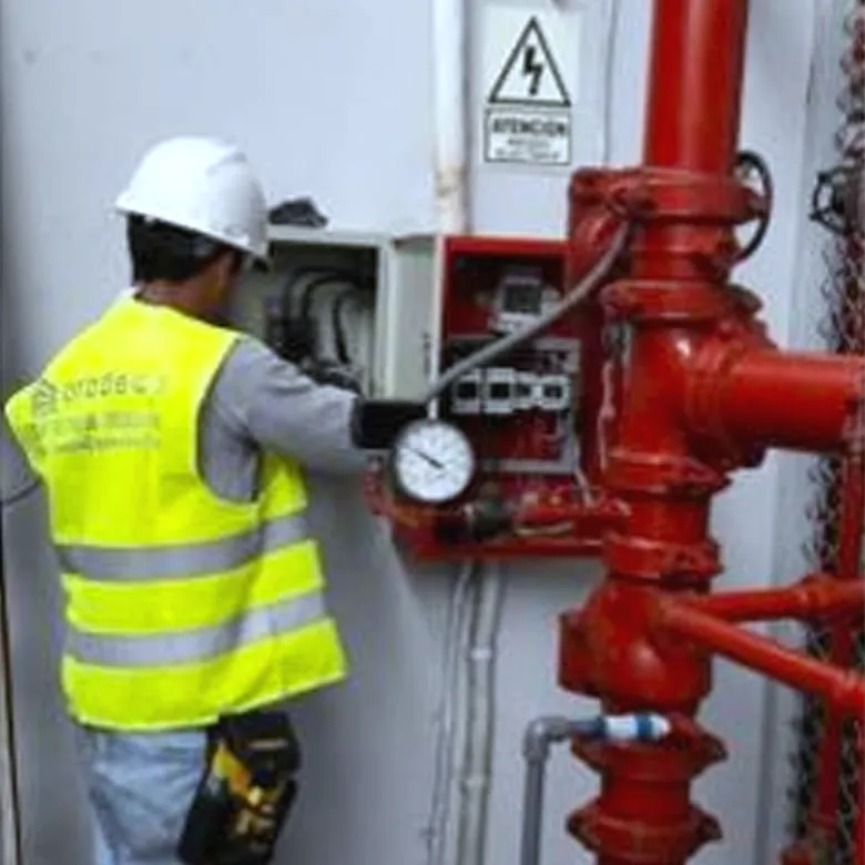 Técnico revisando el manómetro de un montante de agua contra incendio en un local