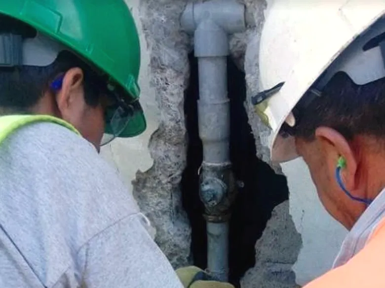 Dos técnicos interviniendo una red de tuberías empotrada tras picar el muro